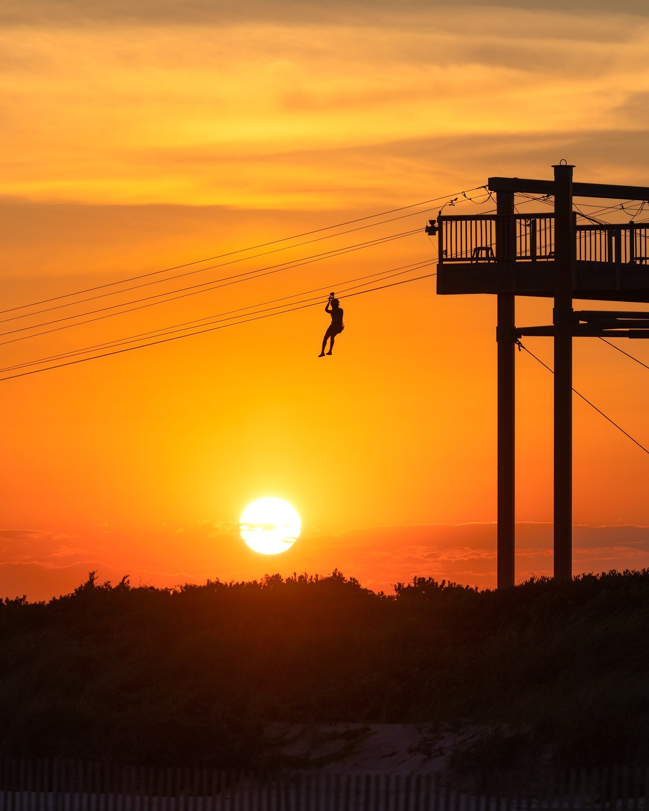 Sunset zipline silhouette over coastal dunes in Cabo